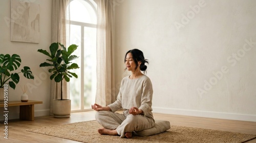 Peaceful Asian woman practicing meditation and mindfulness in a bright, minimalist home interior with natural light and plenty of negative space