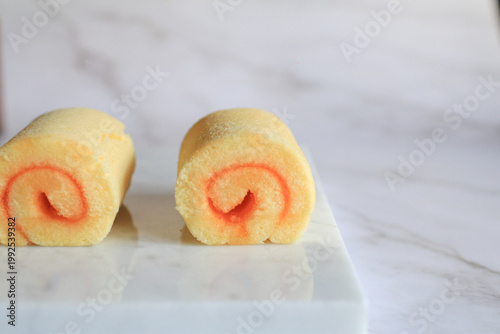 Homemade orange yam rolls on marble table. Soft cake texture. Dessert and bakery.