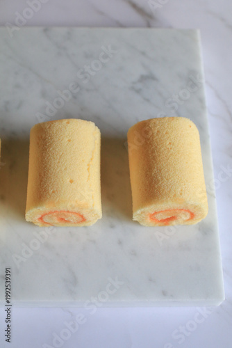 Homemade orange yam rolls on marble table. Soft cake texture. Dessert and bakery.