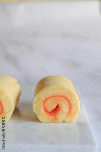 Homemade orange yam rolls on marble table. Soft cake texture. Dessert and bakery.