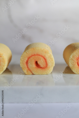 Homemade orange yam rolls on marble table. Soft cake texture. Dessert and bakery.