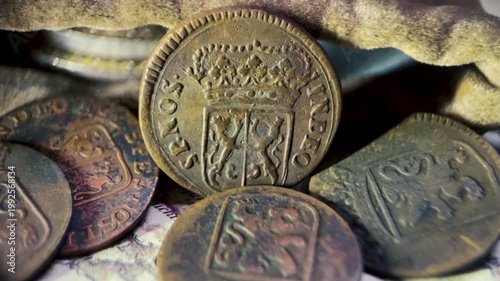 Close up video of an antique VOC 1 duit Gelderland coin showing the obverse side with a crowned shield and the inscription “INDEO SP. NOS.”