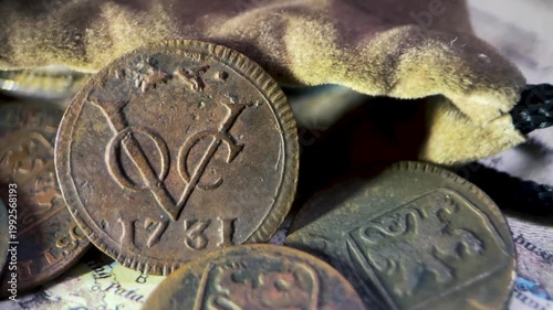 Detailed close up video of an antique 1731 VOC 1 duit coin featuring the classic VOC monogram and fox privy mark, captured from a slanted side angle.