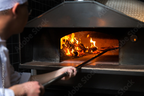 Bild auf Leinwand Wood-Fired Pizza Oven with Chef and Open Flames - Traditional Pizzeria