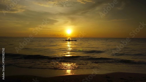 silhouette of Fisherman on Traditional Boat at Golden Sunset Over Tropical Ocean with Sun Reflection