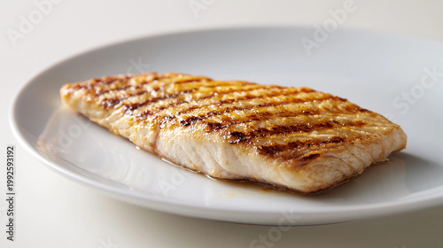 白い皿に盛られた香ばしく焼き上げた白身魚のグリルフィレ