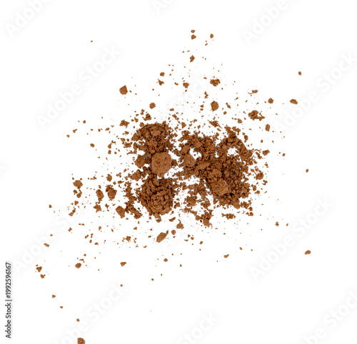 Scattered cocoa powder or coffee grounds. Overhead view of brown crushed powder texture with clumps and fine particles. Concept of food ingredients or cosmetic makeup.