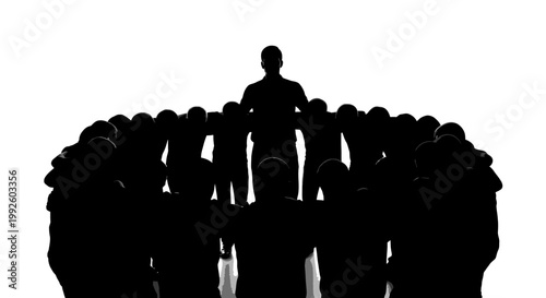 Silhouette of a man standing on a podium addressing a large group of people.