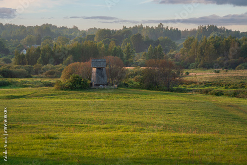 An ancient wooden windmill on the banks of the Sorot River on a foggy summer morning, Mikhailovskoye, Pushkinskiye Gory, Pskov region, Russia