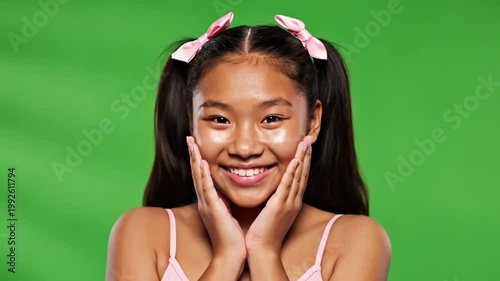 Surprised Asian girl with pigtails and pink bows, green screen background