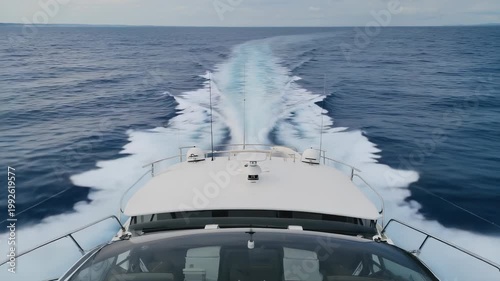 A yacht cuts steadily through open water as white wake trails behind and the clear horizon approaches with growing momentum