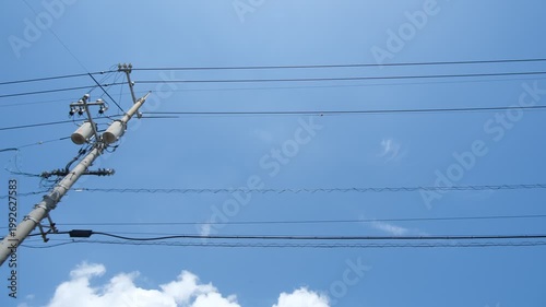 Parallel power lines against blue sky filmed from moving car, upward tracking utility wire footage