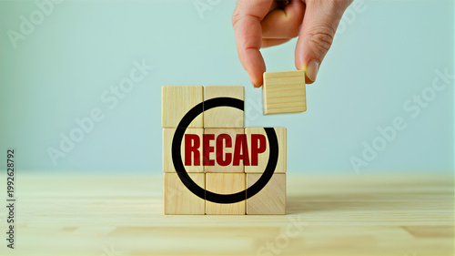 Hand completing a wooden block puzzle with the word 'RECAP' on it, symbolizing a business summary, project review, or the finalization of a task