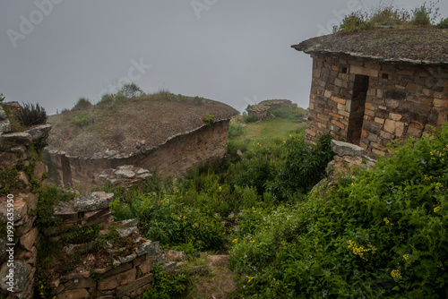 Ancient Stone Houses in Misty Mountain Landscape with Lush Vegetation