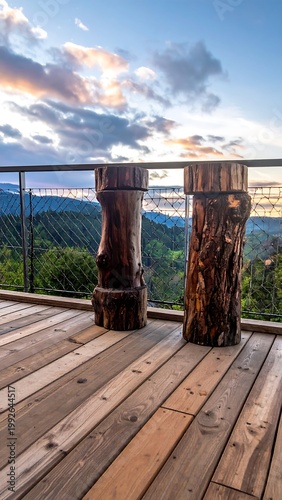 Wooden deck with stump seats overlooking green hills and a city during sunset