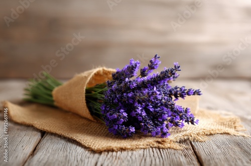 Fresh lavender bouquet wrapped in burlap, resting on weathered wooden planks
