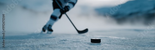 Hockey player skating on ice with a puck in a misty winter landscape