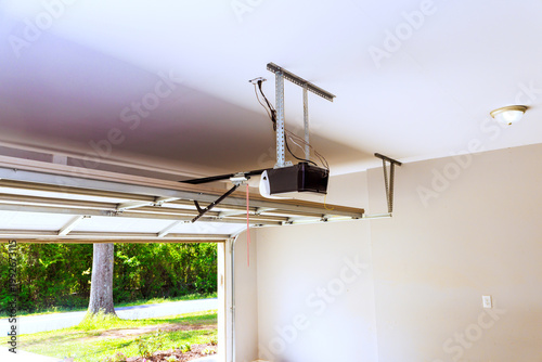 Photos Garage door opener is mounted on ceiling, with door open, allowing to shine in