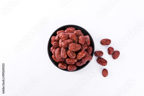 Photography Dried red dates in black bowl on white background top view