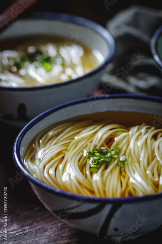 Foto Two bowls of hot noodle soup with scallions on rustic table