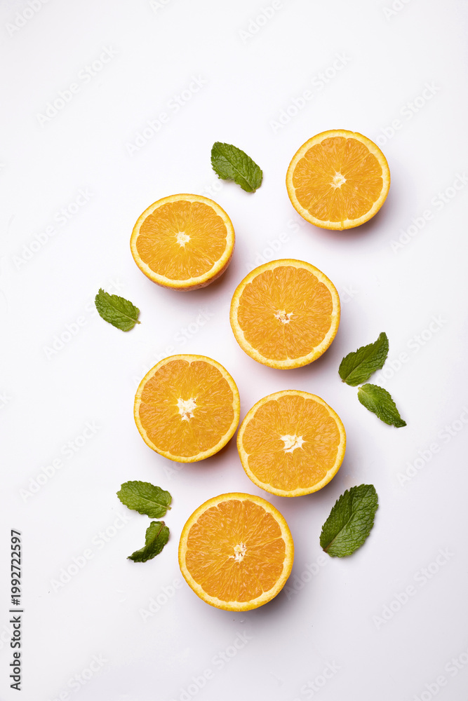 Fototapeta premium Fresh orange halves with mint leaves on light background
