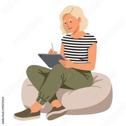 Woman sits on beanbag chair writing on digital tablet indoors