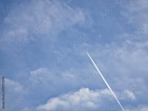 Jet Leaving Thin Contrail Across Cloudy Blue Sky