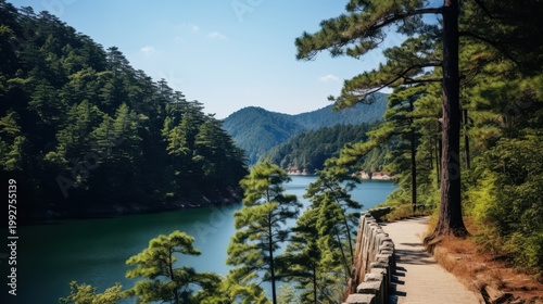 Path along a tranquil lake surrounded by lush green pine forests and mountains.