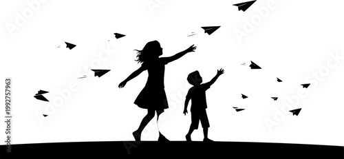 silhouette of siblings playing with paper planes outside at sunset

