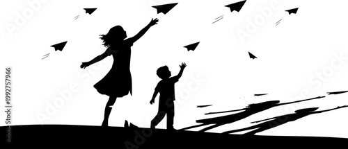 silhouette of siblings playing with paper planes outside at sunset
