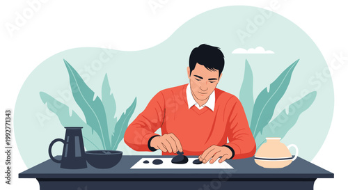 Focused young man in a red sweater sitting at a table and carefully arranging small black stones for a creative or artistic hobby in a room.