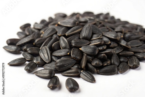Black sunflower seeds piled against a stark white backdrop