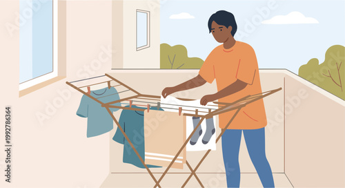 A person hangs clothes on a drying rack on a balcony overlooking trees.