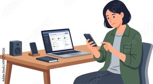 Woman sitting at desk working on laptop and holding phone