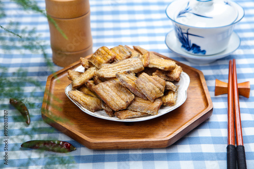 Billede på lærred Crispy fried hairtail fish crackers on plate with chopsticks and tea set