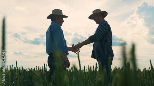 Farmers shaking hands in wheat field, Agriculture partnership on the field, Friendly handshake between farm workers, Rural businessmen agreement, Two men meeting on farm, Wheat field handshake at