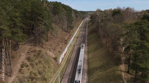 Modern passenger train connecting suburban residential areas with the city center; Efficient commuter rail transport; Daily suburban commuting route through nature; Fast regional transit from city out