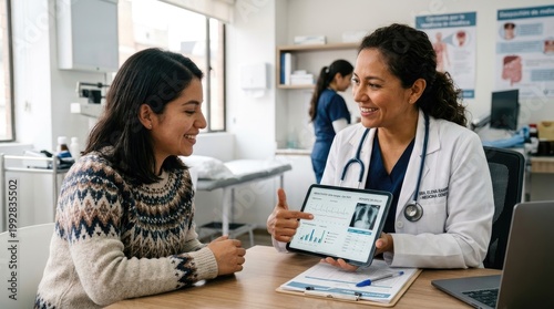 A female doctor and a young woman are engaged in a conversation while reviewing a digital health chart on a tablet.