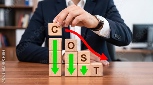 Businessman holding wooden block with letter c to complete the word cost with a downward red arrow indicating cost reduction
