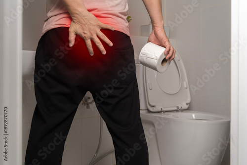 Foto Man with hemorrhoid pain holding toilet paper in bathroom