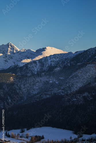 Snowy mountain landscape in winter with clear sky and sunlight shining on peaks in the background. Kasprowy Wierch, Zakopane, Tatra mountains