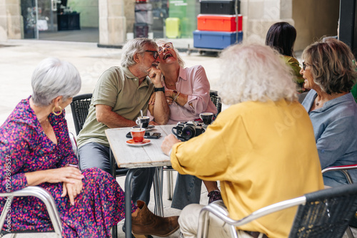 Obraz na płótnie Group of senior friends sitting at an outdoor cafe, laughing and talking while d