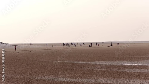 Group of people enjoying leisure time on a vast muddy beach, socotra island