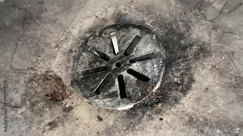 Concrete basement floor drain with metal grate showing indoor plumbing access point and residential utility system detail