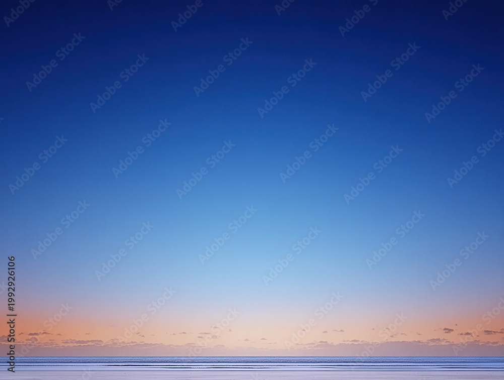 Obraz premium Pastel dawn colors cover the horizon above the ocean surface as day breaks over the water in a quiet moment of morning light