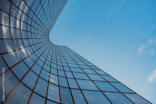 Minimal upward view of modern architecture as glass office skyscraper building facade shows reflection in Paris France with blue sky clean lines and copy space