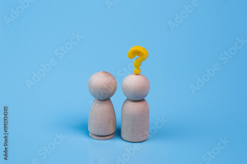 A pair of minimalist wooden figures, one with a yellow question mark, symbolizing curiosity and uncertainty