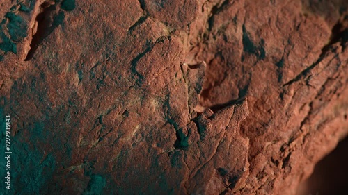 Close-up rock texture with warm tones and green shadow contrast