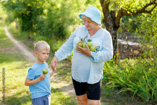 Grandmother holding grandson's hand while carrying fresh pears.