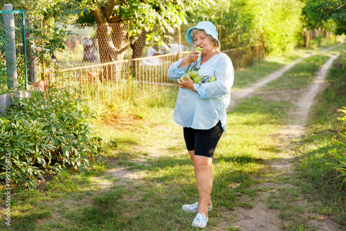 Senior woman enjoying the aroma of a freshly picked organic pear.